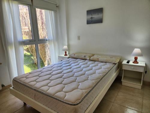 1 cama en un dormitorio con ventana grande en Familiar Pinar Gesell en Villa Gesell