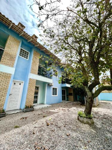 ein blaues Haus mit einem Baum davor in der Unterkunft Férias de Verão - Bombinhas in Bombinhas