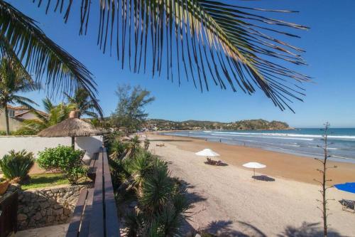 ein Strand mit Sonnenschirmen und Menschen am Strand in der Unterkunft Paraíso Pé na Areia de Geribá com Cinco Suítes Por Luxury Rentals in Búzios