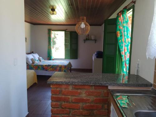 Habitación con cama y cocina con encimera. en Pouso Jambo Rosa, en Valença