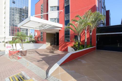 a building with palm trees in front of it at Faro Hotel São José dos Campos in São José dos Campos