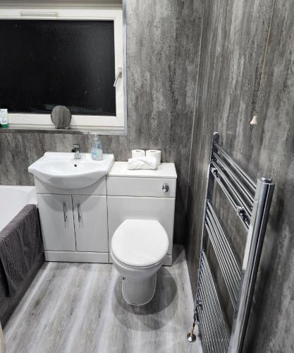 a bathroom with a white toilet and a sink at Stunning 3 bedroom FMHomes & Apartments in Uddingston