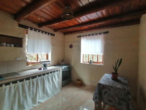 a kitchen with a sink and a table and two windows at Refugio Samay Toa in Hacienda Gualovi