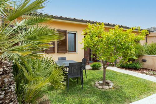 a house with a table and a tree in the yard at [2 KM DAL MARE] Villetta relax con barbecue in Palmadula