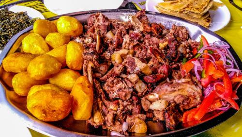 un plato de carne y hortalizas en una mesa en Four Wheels Gardens Hotel & Accommodation en Kitengela 