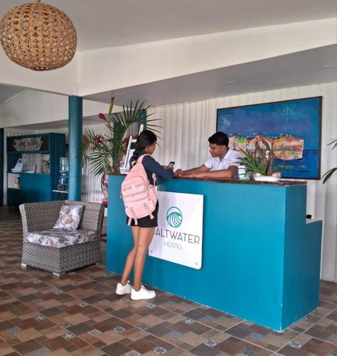 a woman standing at a counter with a man at Hostel SaltWater in San Juan del Sur