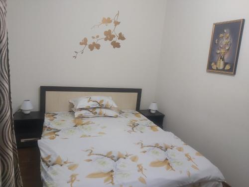 a bedroom with a bed with flowers on the wall at Apartament Sarah in Oţelu Roşu
