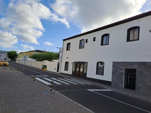 an empty street with a white building and a yellow car at Hotel Ribeira Grande in Ribeira Grande