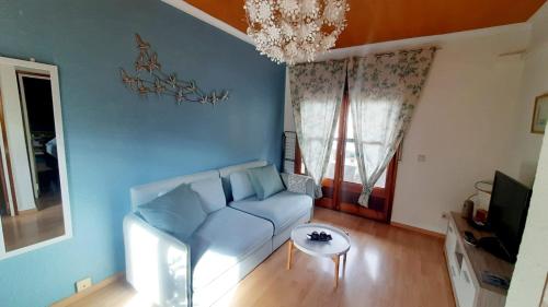 sala de estar con sofá azul y lámpara de araña en Anchoveta, en Calonge