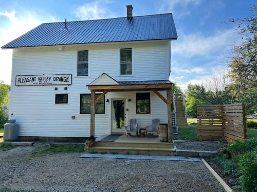 a white house with a porch and chairs on it at Maine Mountain Retreat in Bethel