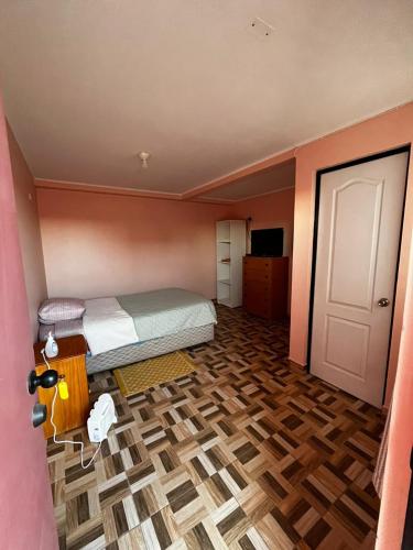 een slaapkamer met een bed en een houten vloer bij Hostal nuevo sol y viento 2 in San Pedro de Atacama