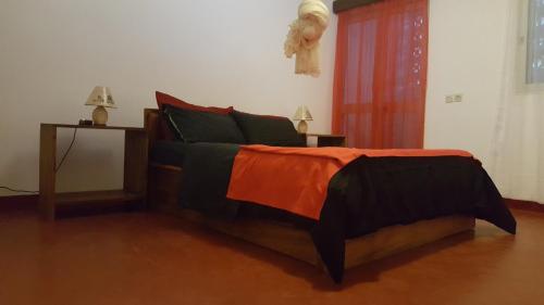 a bedroom with a bed with an orange and black blanket at Villa CALI Napa in Sambava