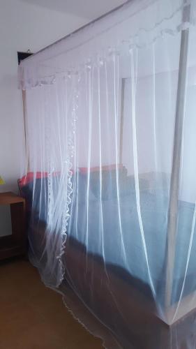 a bedroom with a bed with a white curtain at Villa CALI Napa in Sambava