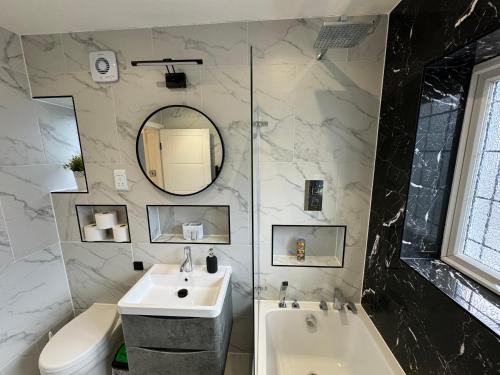 a bathroom with a sink and a tub and a toilet at 3 Bedroom House with Garden in Cheam, London in Cheam