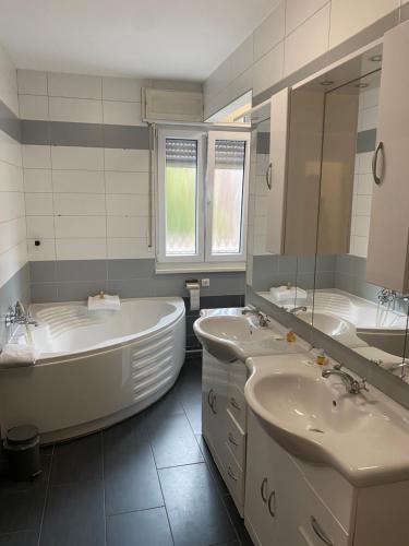 a bathroom with two sinks and a tub and a mirror at Swan Rooms in Nürnberg