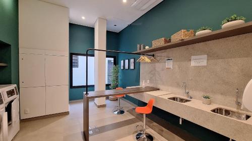 a kitchen with a counter with two sinks and orange chairs at Nex One Ministro Ferreira Alves in Sao Paulo