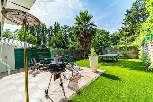 un patio trasero con parrilla, mesa y sillas en Maison Frappaz 4 chambres avec jardin Villeurbanne en Villeurbanne