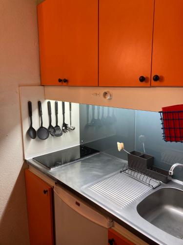 une cuisine avec des armoires orange et un évier dans l'établissement Le Petit La Mongie, à Bagnères-de-Bigorre