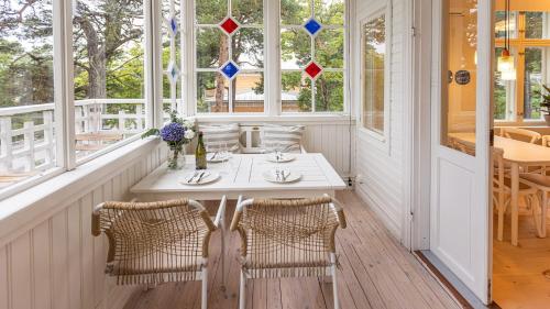 a white table and chairs in a room with windows at Villa Maija 4 Upperside in Hanko