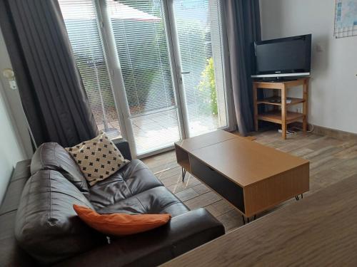 ein Wohnzimmer mit einem Ledersofa und einem Couchtisch in der Unterkunft Studio privé avec terrasse entrée indépendante in Saint-Nazaire