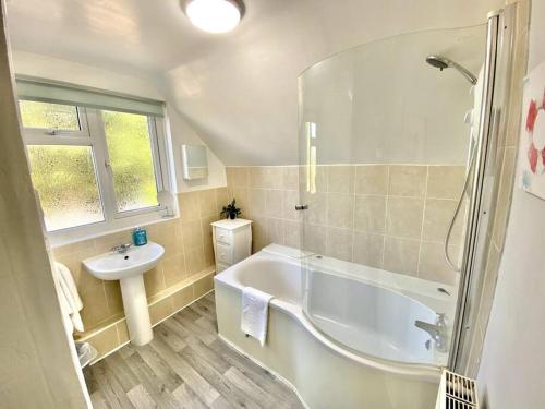 a bathroom with a white tub and a sink at EasyRest - Spacious Detached House - 10 Beds - 5 Bedrooms - 4 Bathrooms - Secure Parking 5 Vehicles - Excellent Road Links - Perfect for Contractors & Large Groups in Grantham