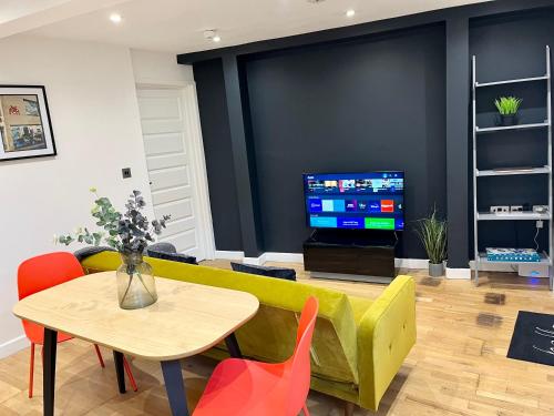 a living room with a couch and a table and a tv at Palmer Apartment, 3 guests, Free Wifi, Great Transport Links, close to Uni, Hospital & Town Centre in Reading