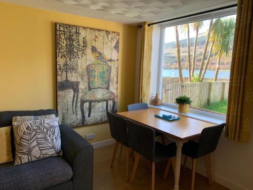 a living room with a table and a chair and a window at Arrochar Alps Apartment in Arrochar