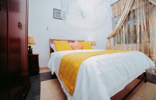 a bedroom with a bed with yellow and white sheets at City Hill Hotel in Bujumbura