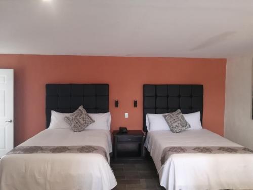 2 camas en una habitación con paredes de color naranja en Hotel Express Inn, en Sabinas