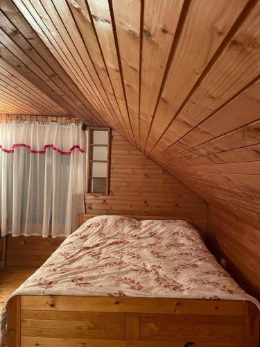 a bed in a room with a wooden ceiling at Vikendica Savic TKM in Pale