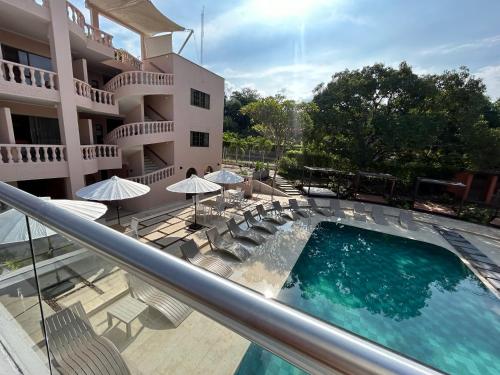 un balcón con piscina, sillas y sombrillas en Del Trópico sopetrán en Sopetran