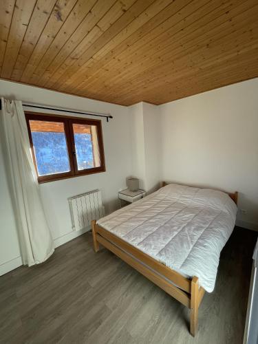 a bedroom with a bed and a wooden ceiling at Chalet Saint-Patrick - Le Cosy in Vars
