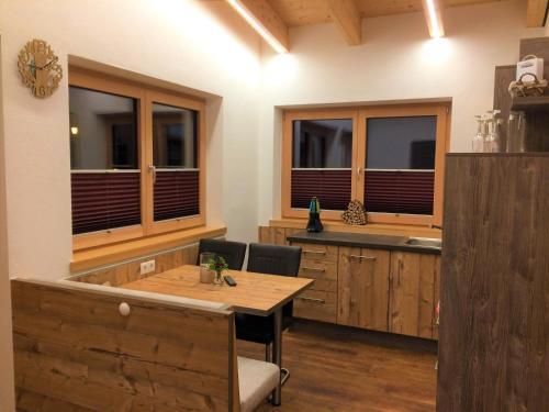 eine Küche mit einem Holztisch, Stühlen und Fenstern in der Unterkunft Haus Bergjuwel in Huben