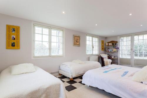 une chambre avec deux lits et deux fenêtres dans l'établissement Face plage, vue mer, jardin - Deauville, à Benerville-sur-Mer