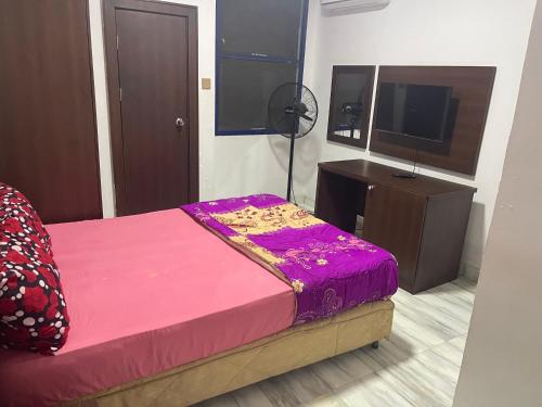 a bedroom with a pink bed and a flat screen tv at Ibiyemi Apartment in Abuja