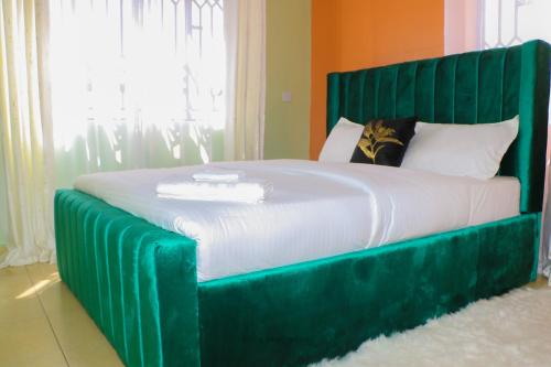 een bed met een groen hoofdeinde in een slaapkamer bij City's Apartment 1 and 2 bedroom in Kisumu