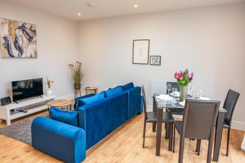 een woonkamer met een blauwe bank en een tafel bij Apartment by the Royal Ramsgate Harbour - Sleeps 4 in Kent