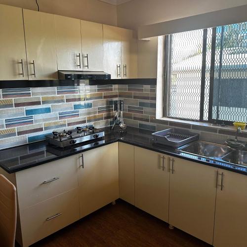 a kitchen with white cabinets and a sink and a window at KumarVacation Home 38 Kennedy Road Unit 2 in Nadi