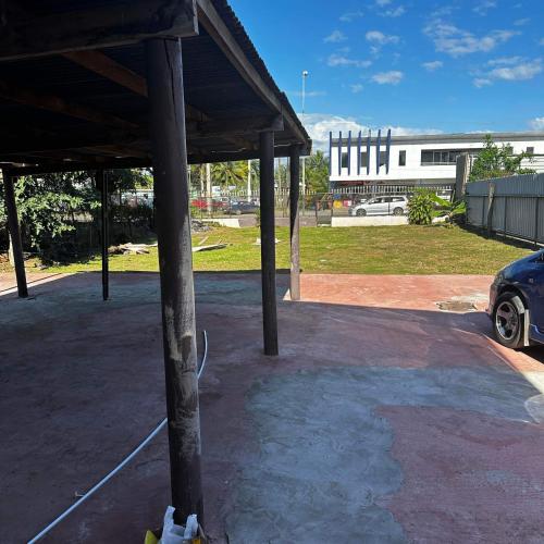 ein überdachter Parkplatz mit einem Gebäude im Hintergrund in der Unterkunft KumarVacation Home 38 Kennedy Road Unit 2 in Nadi