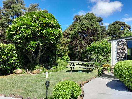 a picnic table and a bench in a garden at Kuaotunu's Peebles Cottage in Kuaotunu