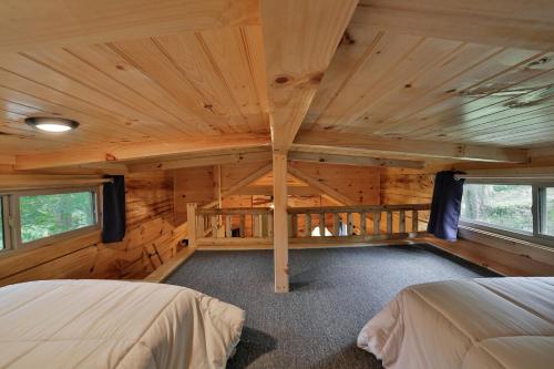 - une chambre dans une cabane en rondins avec 2 lits dans l'établissement Thomas Cabin Forest Tiny Cabin With Hot Tub, à Chattanooga