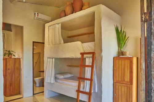 a bunk bed in a room with a ladder at Evoé Caraíva in Caraíva