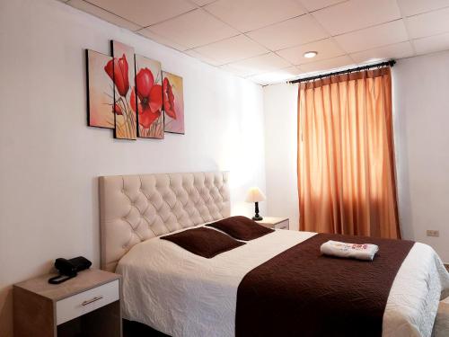1 dormitorio con 1 cama con flores rojas en la pared en HOSTAL MURGEON BOUTIQUE, en Quito