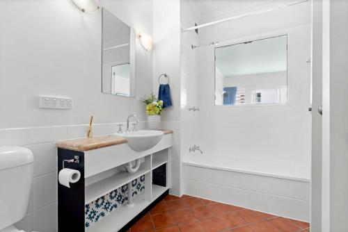 a white bathroom with a sink and a shower at Villa Vaucluse Apartments in Cairns