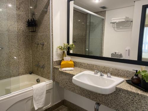 a bathroom with a sink and a tub and a mirror at Flat Jardins, entre Av Paulista e Parque do Ibiraquera in São Paulo