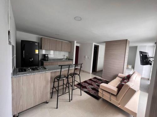 a kitchen and living room with a bar and chairs at Cómodo apartaestudio in Manizales