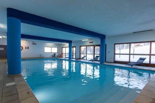 une grande piscine aux murs bleus et aux fenêtres dans l'établissement Appartement Duplex T3 6 personnes les Orres 1800 Tout Confort Pied des Pistes, aux Orres