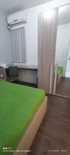 CITRA INN في Teko: مكتب فيه سرير اخضر ومكتب وكراسي