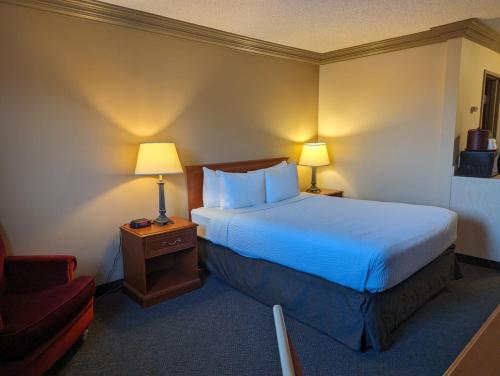 a hotel room with a bed and a chair at Nomad Hotel & Suites in Fort McMurray