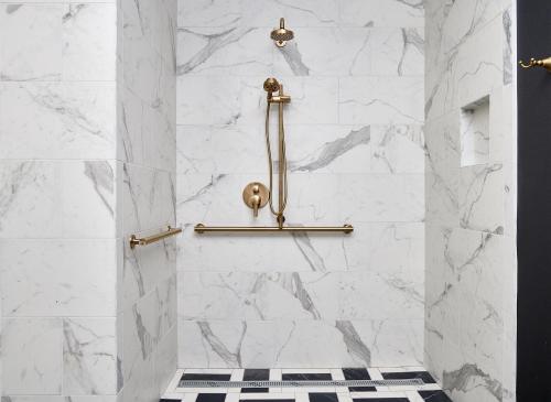 a shower with white marble walls and gold fixtures at The Radical Asheville, Tapestry Collection by Hilton in Asheville